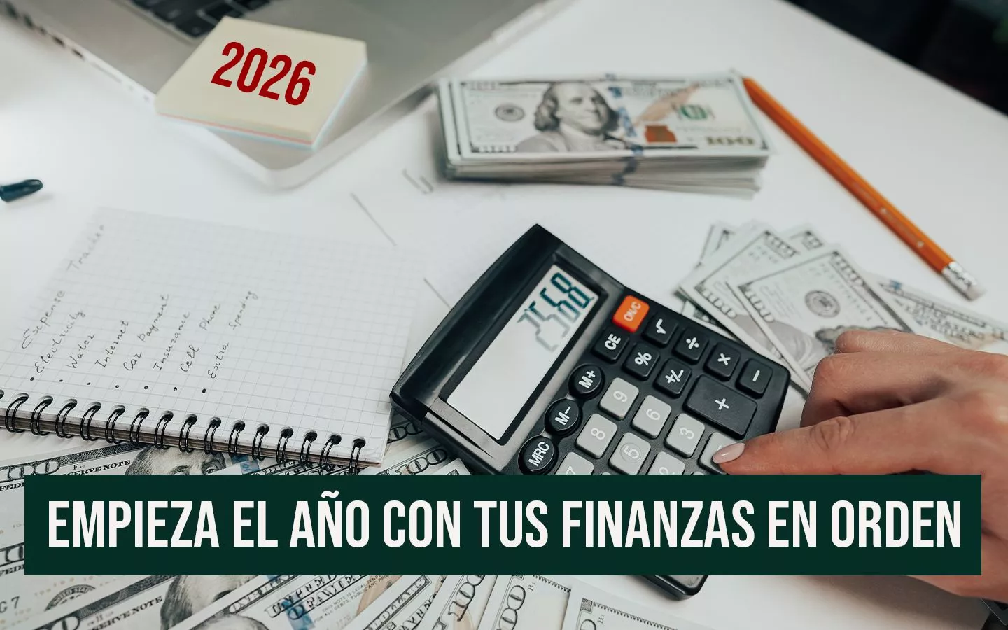 Escritorio con calculadora, billetes de 100 dólares, cuaderno de seguimiento de gastos con el año 2026 y la frase 'Empieza el año con tus finanzas en orden' de Anualidades.