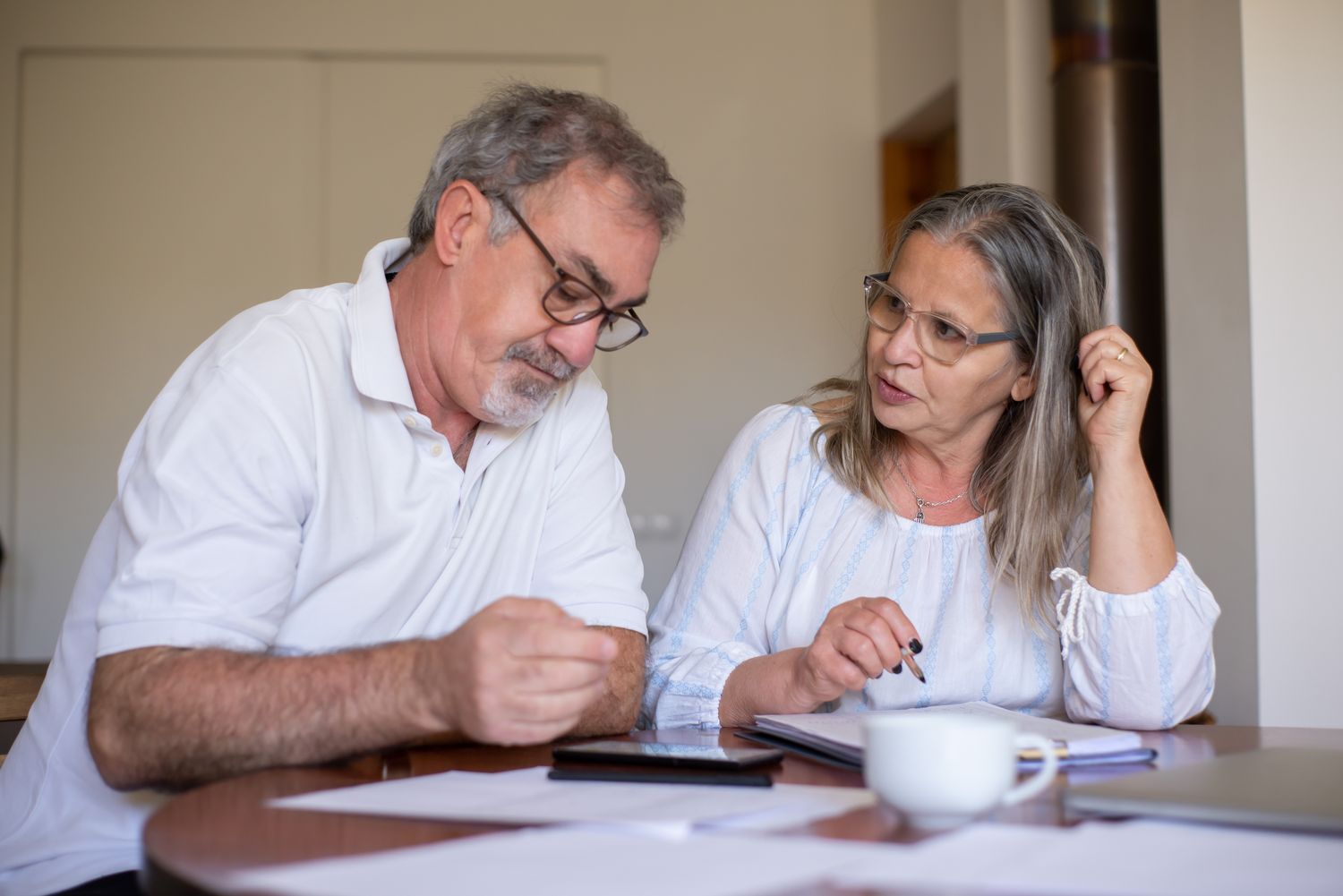Pareja adulta revisando documentos y gastos del hogar ante el aumento de quiebras en Puerto Rico.